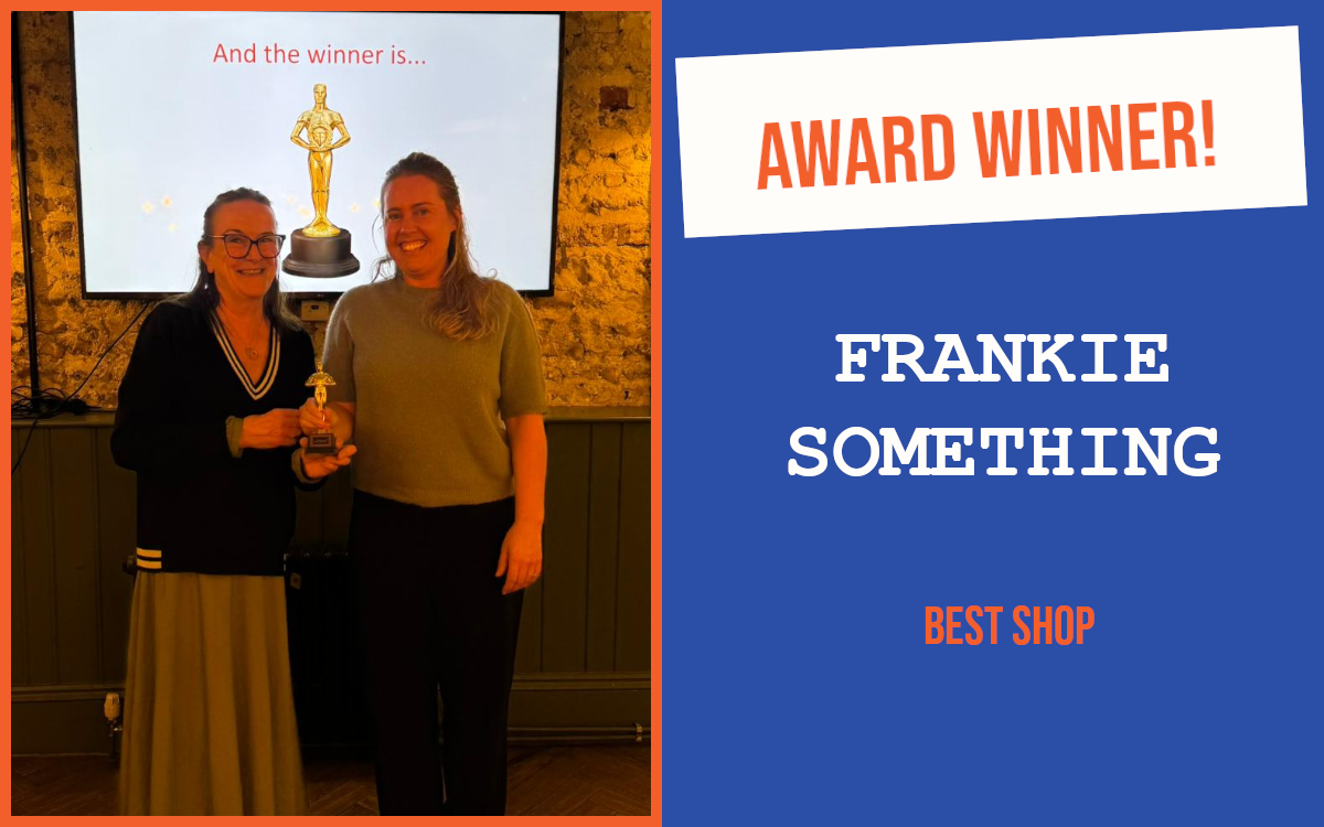 The winner of the networking question at Worthing's April networking event, holding the trophy and standing in front of a screen showing a trophy, with the meeting host.