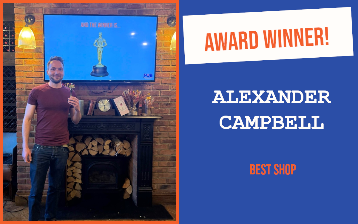 The winner of the evening's question at the April Cambridge networking event, standing in front of a fireplace, holding the trophy. Behind them is a screen displaying a trophy.