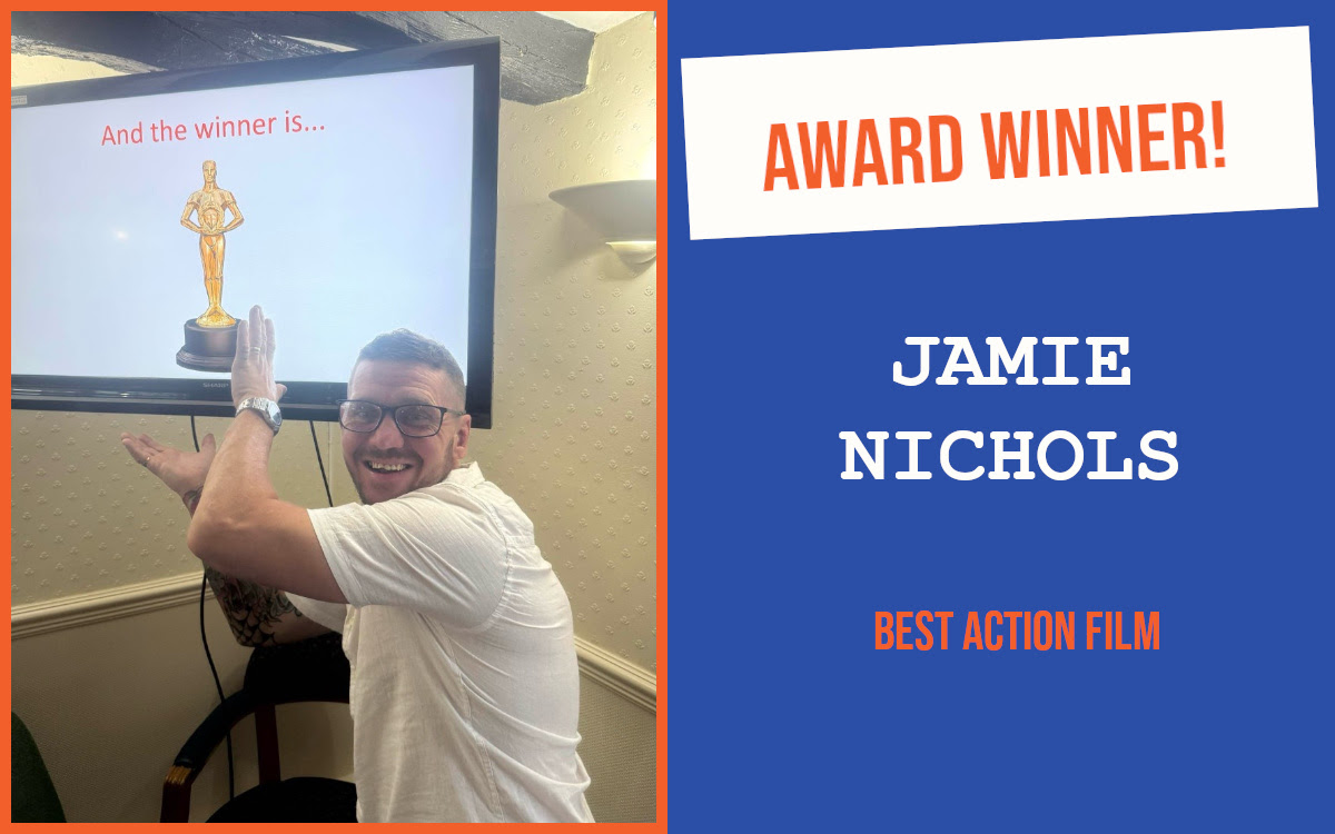 The winner of the networking question at the June meeting of the South East Essex PubNetworking event, in front of a screen showing a trophy.