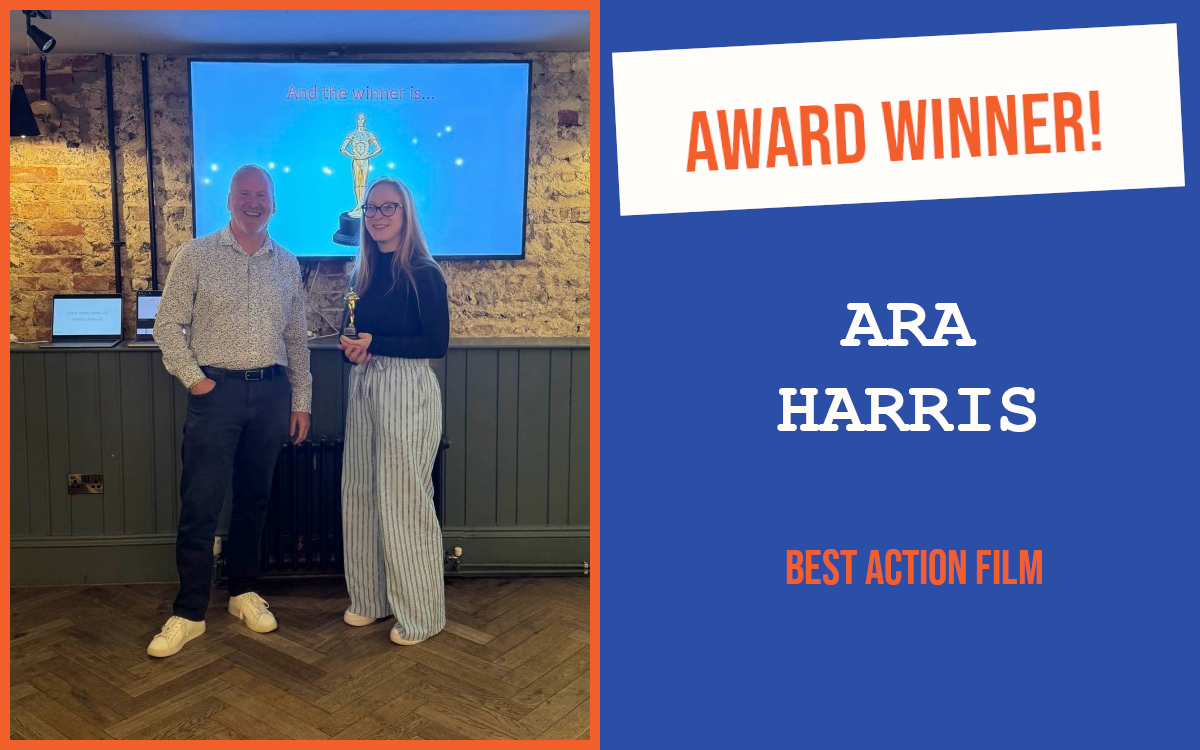 The host of Worthing's PubNetworking event with the winner of the June networking question, holding the trophy and standing in front of a large screen which also displays a trophy.