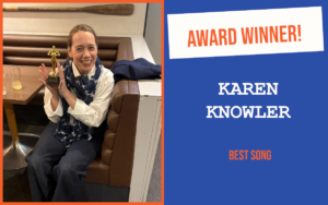 The winner of the introductory question at Ely's September networking event, sitting on a bench seat at a pub table, holding the trophy and looking delighted.
