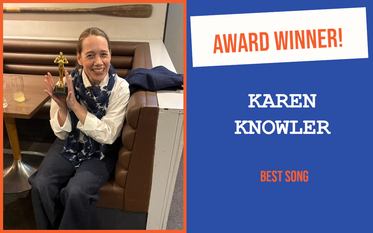 The winner of the introductory question at Ely's September networking event, sitting on a bench seat at a pub table, holding the trophy and looking delighted.