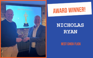 The winner of the introductory question at Worthing's October networking meeting, holding the trophy with the host and standing in front of a screen displaying a trophy.